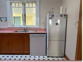 A kitchen with a sink, refrigerator, and dishwasher at The Beach House - Paihia