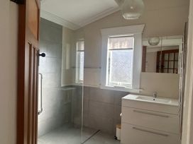 A bathroom with a shower and washbasin at The Beach House - Paihia