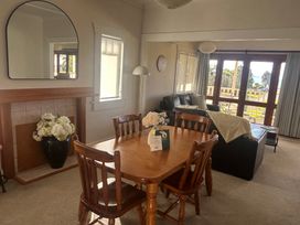 A living room with a dining table and chairs at The Beach House - Paihia Holiday Home in Paihia