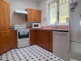 A kitchen with cabinets, stove, sink and refrigerator at The Beach House - Paihia