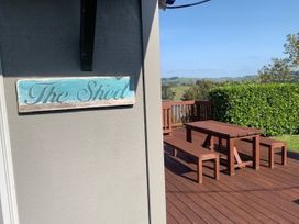 A sign reading The Shed and a table with benches at The Shed - Raglan Holiday Home in Raglan