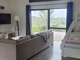 A living room with a sofa, television, and a view at Mangawhai Magic - Mangawhai Heads