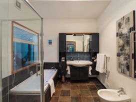 A bathroom with a shower, bathtub, washbasin, and mirrors at Omaha Beach House in Omaha