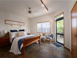A bedroom with a bed, chair, and window at Omaha Beach House - Omaha