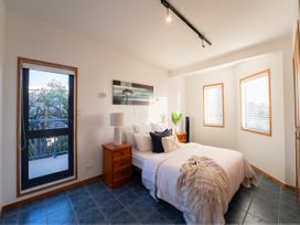 A bedroom with a bed, nightstand, and window at Omaha Beach House - Omaha Holiday Home