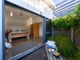 A bedroom with a bed and side tables at Omaha Beach House - Omaha Holiday Home