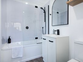 A bathroom with a bathtub, shower, sink, and toilet at Sun Kissed Pool Villa - Mangawhai Heads