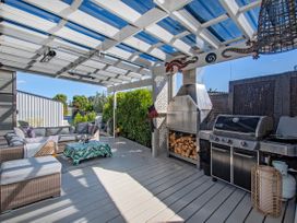 An outdoor patio with seating and barbecue grill at Sun Kissed Pool Villa - Mangawhai Heads