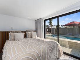 A bedroom with a bed and window overlooking a pool at Sun Kissed Pool Villa - Mangawhai Heads