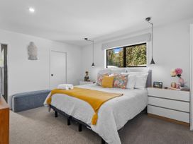 A bedroom with a bed and bedside table at Sun Kissed Pool Villa - Mangawhai Holiday Home, Mangawhai Heads