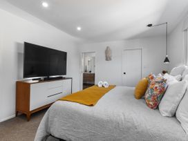 A bedroom with a television and a bed at Sun Kissed Pool Villa - Mangawhai Heads