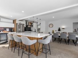 A kitchen with bar stools and a dining table at Sun Kissed Pool Villa - Mangawhai Holiday Home Mangawhai Heads