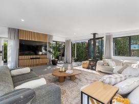 A living room with a sofa, coffee table, and television at Sun Kissed Pool Villa - Mangawhai Heads