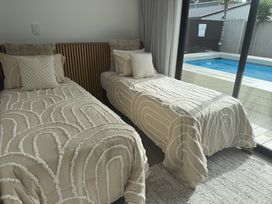 A bedroom with two beds and a view of a swimming pool at Sun Kissed Pool Villa - Mangawhai Heads