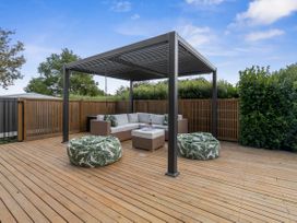 An outdoor lounge area with a pergola and cushioned seating at House Naomi - Martinborough Holiday Home Martinborough