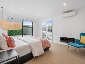 A bedroom with a bed, bedside table, chair and tv at House Naomi - Martinborough Holiday Home, Martinborough