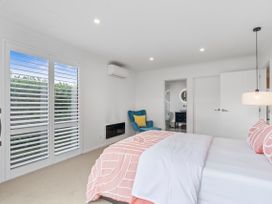 A bedroom with a bed and chair at House Naomi - Martinborough Holiday Home Martinborough