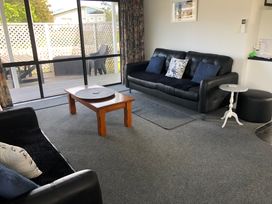 A living room with a sofa and coffee table at Beach Life - Whangamata Holiday Home in Whangamata