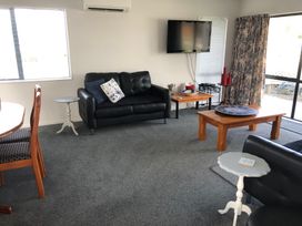A living room with a sofa and coffee table at Beach Life - Whangamata Holiday Home in Whangamata