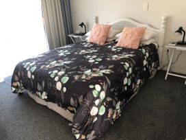 A bedroom with a bed and side table at Beach Life - Whangamata Holiday Home in Whangamata