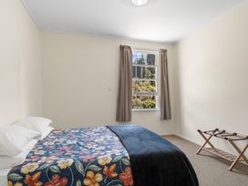 A bedroom with a bed and window at Kauri Cottage at Marble Hills - Marahau
