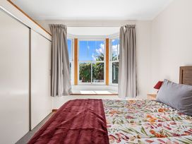A bedroom with a bed and window at Kauri Cottage at Marble Hills - Marahau