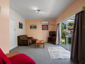 A living room with a sofa, coffee table, and television at Kauri Cottage at Marble Hills - Marahau