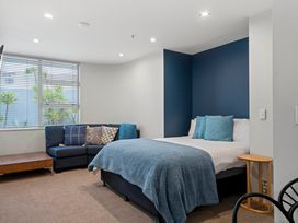 A bedroom with a bed and sofa at Waimahana 5 - Taupo Holiday Apartment Waipahihi