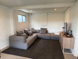 A living room with a sofa and television at Sol Vista Paku - Pauanui Holiday Home
