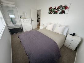 A bedroom with a bed and dresser at Sol Vista Paku - Pauanui Holiday Home Pauanui