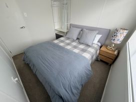A bedroom with a bed and bedside table at Sol Vista Paku - Pauanui Holiday Home Pauanui
