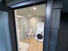 A laundry room with a shower, toilet, washing machine, and dryer at Sol Vista Paku - Pauanui Holiday Home