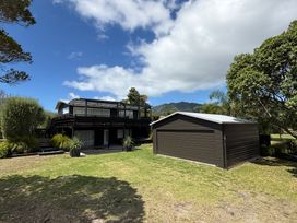 A house and garage with trees in the yard at Sol Vista Paku - Pauanui Holiday Home Pauanui