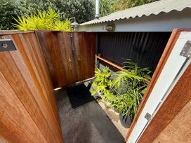 An outdoor shower area with wooden enclosure and plants at Sol Vista Paku - Pauanui
