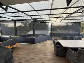 An outdoor deck with seating and a table at Sol Vista Paku - Pauanui Holiday Home Pauanui