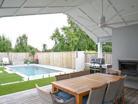 An outdoor dining area with a table and chairs near a swimming pool at Modern Deluxe - Havelock North Holiday Home Havelock North