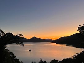 A scenic view of a lake with mountains and a boat at Moetapu Bay Bliss - Marlborough Sounds Retreat, Moetapu Bay