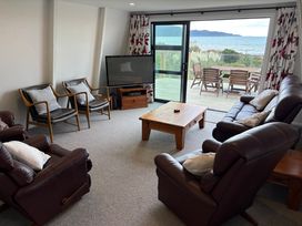 A living room with a television and sliding door at Sunset Shores - Paraparaumu Beach Retreat