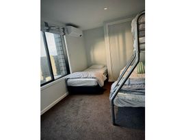 A bedroom with a single bed and a bunk bed at Beachfront Paradise - Papamoa Beach Holiday Home, Papamoa