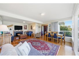 A living room with a sofa and dining area at Bayview Beauty - Charteris Bay
