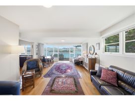 A living room with a sofa and dining table at Bayview Beauty - Charteris Bay Holiday Home Charteris Bay