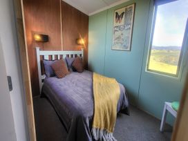 A bedroom with a bed and window view at Heart of Waipu - Waipu