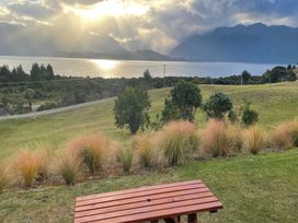 A red table with grass and trees overlooking a lake and mountains at Southland Sanctuary - Te Anau Holiday Home Fiordland