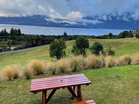 A picnic table near a lake with mountains in the background at Southland Sanctuary - Te Anau Holiday Home Fiordland