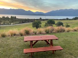 A picnic table with benches overlooking a lake and mountain range at Southland Sanctuary - Te Anau Holiday Home, Fiordland