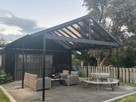An outdoor seating area with a table and chairs at The Bach at 44 - Cooks Beach Holiday Home Cooks Beach