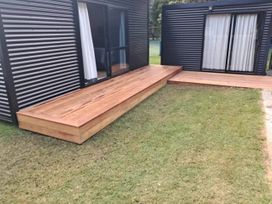 A deck adjacent to a grass area at The Bach at 44 - Cooks Beach Holiday Home Cooks Beach