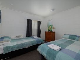 A bedroom with two beds and a wooden drawer at Te Tiriti Beach House - Paihia