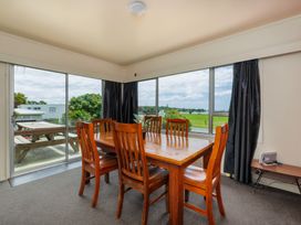 A dining room with a wooden table and chairs at Te Tiriti Beach House - Paihia