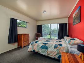 A bedroom with a bed and dresser at Te Tiriti Beach House - Paihia